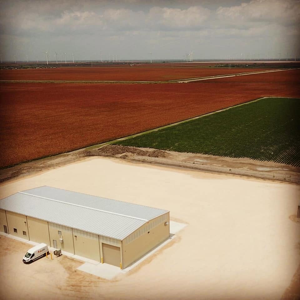 Aerial view of a commercial metal building served by Electro Cooling Service with an ELCO van on site in the Rio Grande Valley