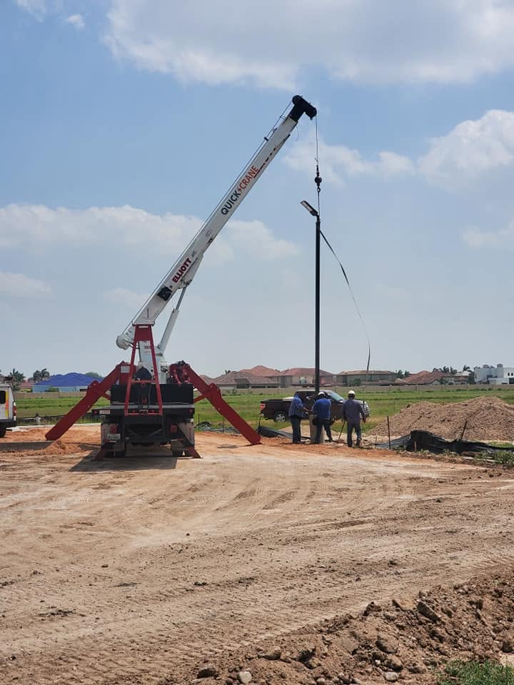 Electro Cooling Service crane lifting a parking-lot light pole into place on a commercial job site in the Rio Grande Valley